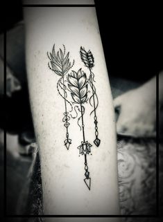 a black and white photo of a tattoo with flowers on the arm, which has an arrow