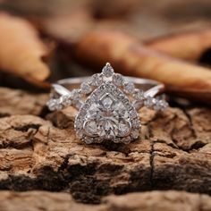 a pear shaped diamond ring sitting on top of a piece of wood