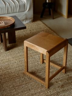 two wooden tables sitting on top of a carpeted floor next to a white couch