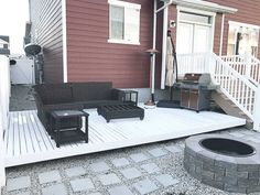 a deck with chairs and fire pit in front of a red house next to stairs