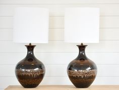 two brown and white vases sitting on top of a wooden table next to each other