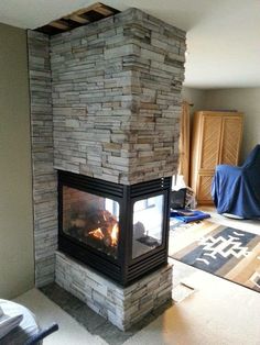 a fire place in the middle of a living room with a couch and rugs on the floor