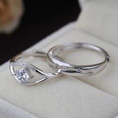 two wedding rings sitting on top of a white velvet cushioned surface with a cat in the background