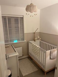 a baby's room with a white crib and gray carpeted flooring