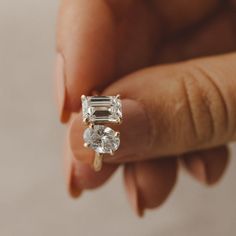 a woman's hand holding an engagement ring with three stones on the top and bottom