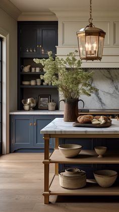 a kitchen with blue cabinets and marble counter tops, an island in the middle has bowls on it