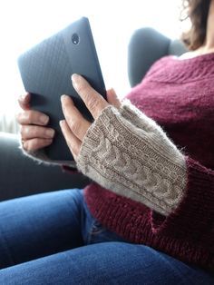 a woman sitting on a couch holding an electronic device in her hands and looking at the screen