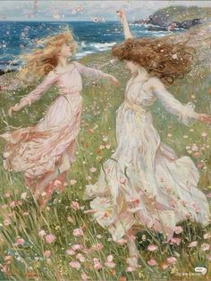 two women in white dresses are walking through the grass by the ocean with pink flowers