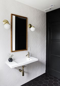 a white sink sitting under a mirror next to a wall mounted faucet in a bathroom