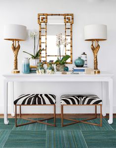 a white table with two zebra stools and a mirror on the wall above it