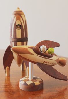 two wooden toys are sitting on top of a table, one has a banana and the other is a rocket ship