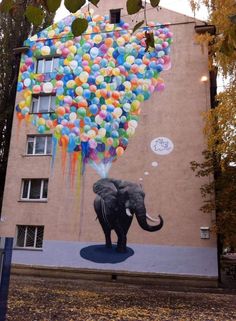 an elephant is painted on the side of a building with balloons floating in the air