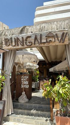 an entrance to a restaurant with umbrellas and plants