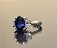 Dekara Designs Collection Metal- 90% Platinum, 10% Iridium. Stones- 1 Natural Untreated 3.88 Carat Oval Cut Ceylon Blue Sapphire. 2 Moon Cut Diamonds, F-G Color VS1 Clarity 0.77 total carats This ring is a size 6, but could be sized up or down a few sizes. This ring could be made in your specific size within 5-10 business days. Could take a little more time due to the ceylon sapphire being a rare stone. The sapphire may be a bit smaller or bigger. We can make the same design in a smaller or bigg Oval Blue Diamond Ring With Accent Stones, Classic Blue Rings With Lab-created Sapphire, Classic Blue Lab-created Sapphire Rings, Blue Sapphire Wedding Ring With Brilliant Cut, Blue Gia Certified Diamond Ring For Formal Occasions, Blue Sapphire Ring With Brilliant Oval Cut, Blue Diamond Ring With Vvs Clarity, Blue Oval Diamond Ring With Prong Setting, Blue Oval Diamond Ring With Center Stone