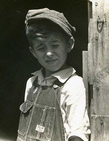 an old black and white photo of a young boy holding something in his right hand