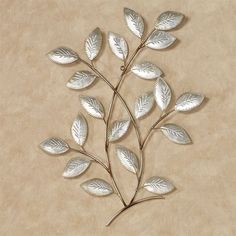 a metal branch with leaves on it sitting on a table next to a brown wall