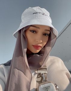 a woman wearing a white hat and holding a cell phone in her right hand while standing next to an airplane