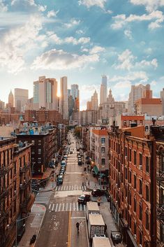 a city street filled with lots of traffic and tall buildings under a cloudy blue sky