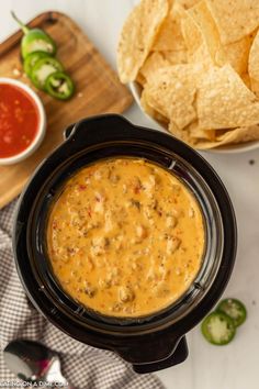 a crock pot filled with tortilla chips next to a bowl of salsa