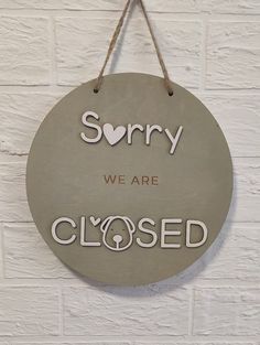 a sign that says sorry we are closed hanging on a brick wall