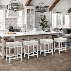 a kitchen with white counter tops and stools next to an island in the middle