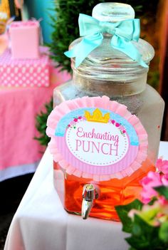 there is a punch bottle on the table with pink and blue flowers in front of it