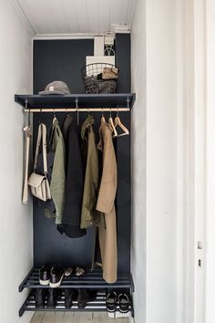 a coat rack with shoes and coats hanging on it in a white walled entryway