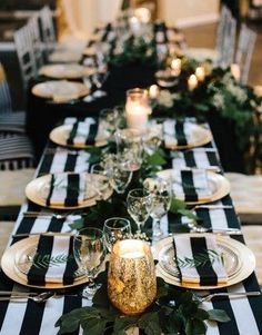 a long table with black and white striped linens, candles and greenery on it