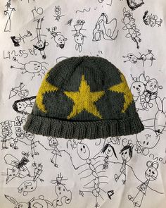 a knitted hat with yellow stars on it sitting on top of a sheet of paper