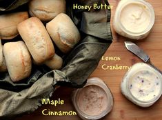 breads and dips are sitting on a wooden table next to a bag with honey butter, lemon cranberry