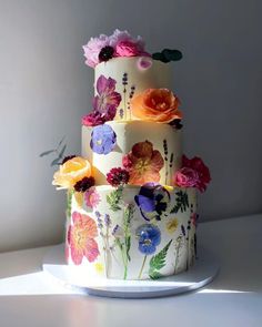 a three tiered cake with flowers painted on it