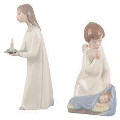 two ceramic figurines of the same person holding a candle, one with a baby on it's lap