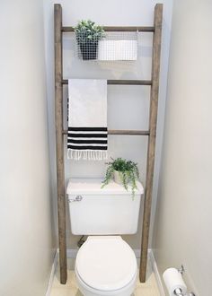 a white toilet sitting in a bathroom next to a wooden shelf with plants on it