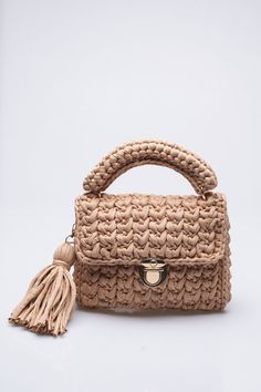 a beige handbag with a tasselled handle