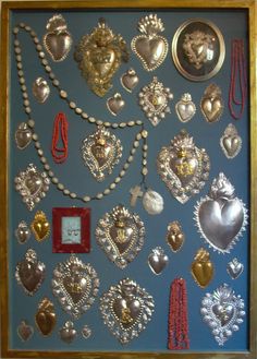 a blue wall covered in lots of different types of necklaces and brooches