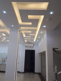 an empty hallway with white walls and ceiling lights on the ceiling is lit by recessed lighting