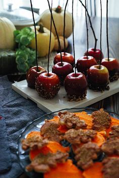 there are many apples on the plate and some other food items in the background with sticks sticking out of them