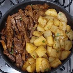 some meat and potatoes in a pan on the stove