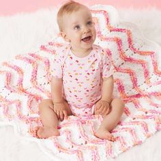 a baby sitting on a blanket smiling at the camera