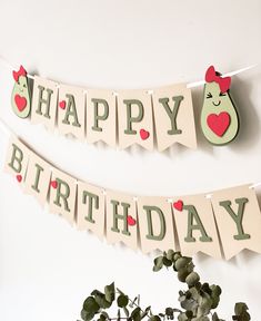 two happy birthday banners hanging on a wall next to a potted plant and vase with flowers