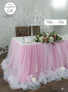 a table with pink tulle and white flowers on it, surrounded by candlesticks