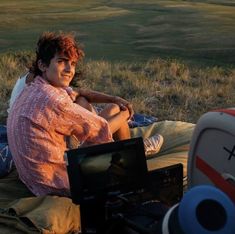 a woman sitting on top of a blanket next to a laptop computer