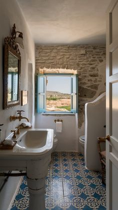 a bathroom with blue and white tile flooring next to a window that looks out onto the desert