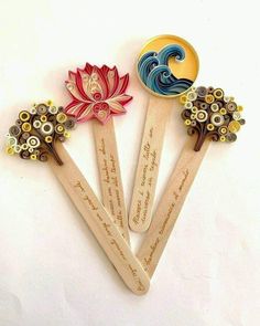 four wooden spoons with designs on them sitting next to each other and one has a flower in the middle