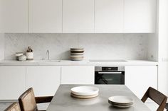 a table with plates and bowls on it in the middle of a white kitchen area