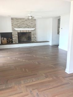 an empty living room with wood floors and a fireplace