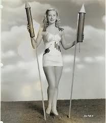 an old photo of a woman holding two rockets in one hand and a rocket in the other