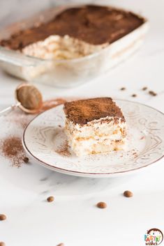 a piece of cake sitting on top of a white plate next to a bowl of nuts