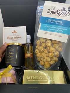 a person is holding a box with some snacks in it and a bottle of wine next to it