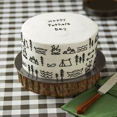 a white cake with black designs on it sitting on a table next to a knife